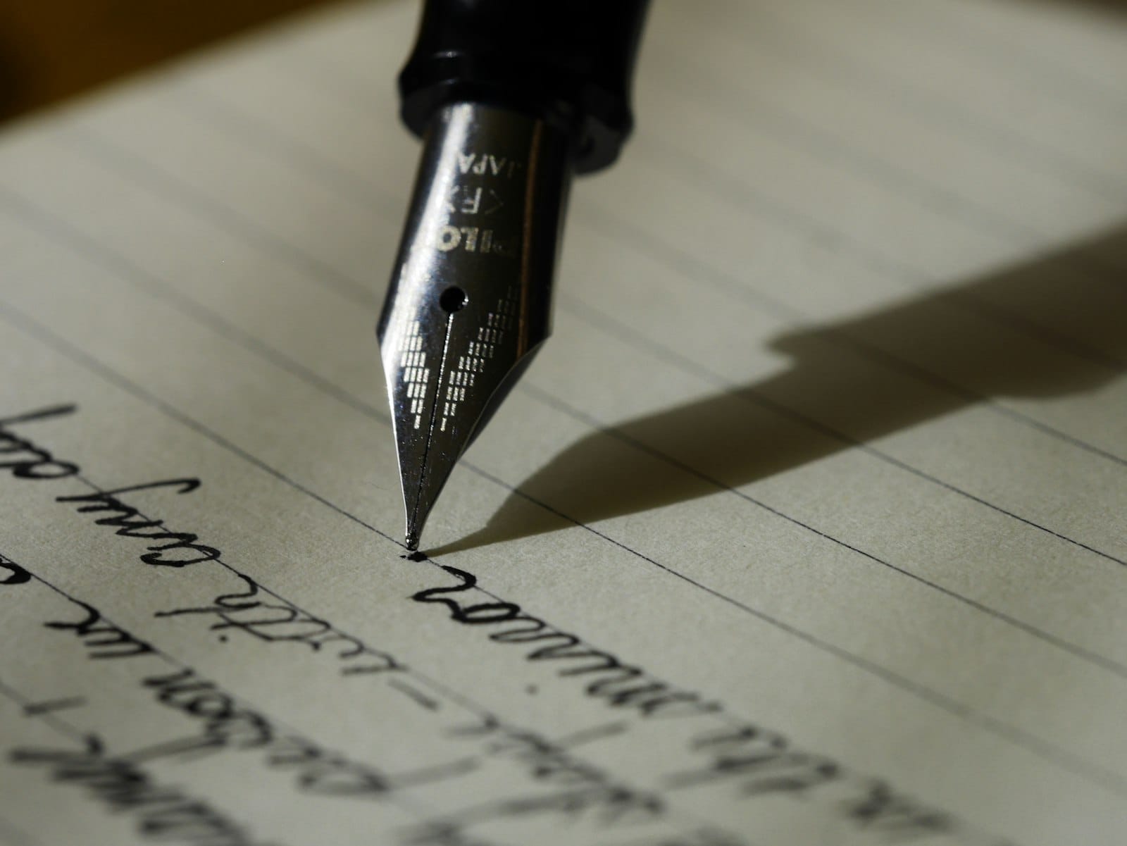 A handwritten letter and fountain pen resting on a wooden desk